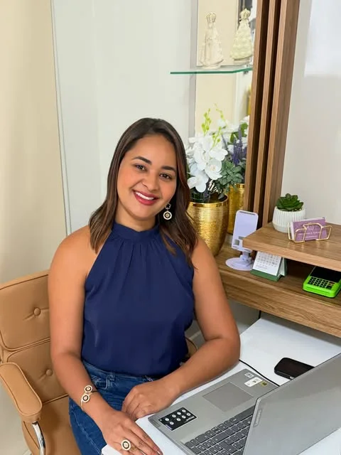 Dra. Adriele Tâmara sentada à mesa do consultório
